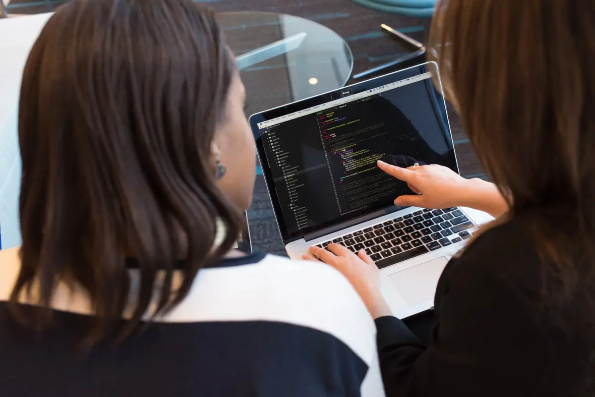 Two people reviewing code together on a laptop screen