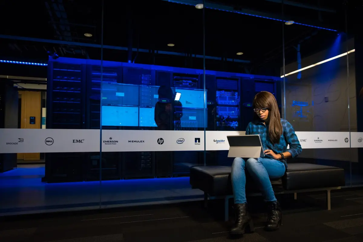 A woman working on a laptop in a darkened technology venue