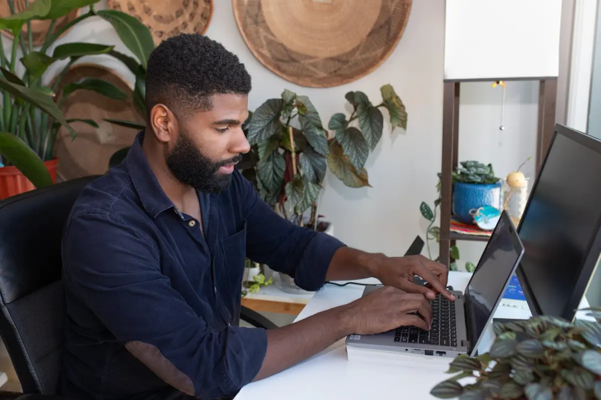 A man concentrating at a laptop in a plant filled room