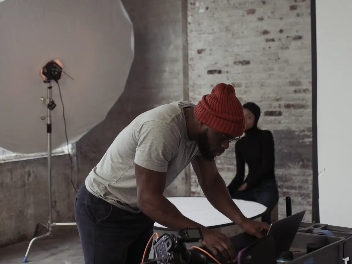 Two people setting up equipment around a laptop in a studio